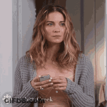 Woman In Grey Sweater Holding Cell Phone GIF