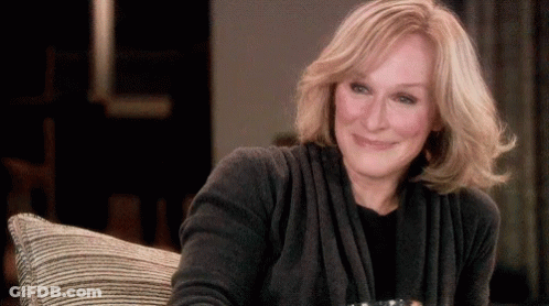 Woman In Grey Sweater Smiling On Couch GIF