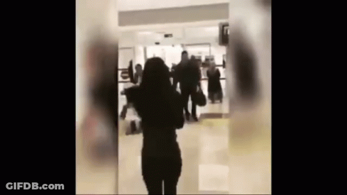 Woman In Hallway With People Walking GIF