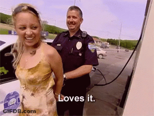 Woman In Handcuffs Smiling Next To Police Officer Saying Loves It GIF