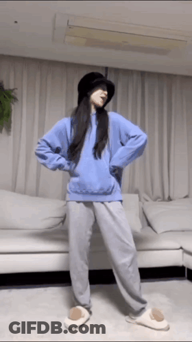 Woman In Hat And Blue Hoodie Dancing In Living Room GIF