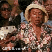 Woman In Hat And Floral Jacket Standing In Crowd GIF