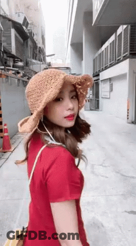 Woman In Hat And Red Shirt Walking Down Street GIF