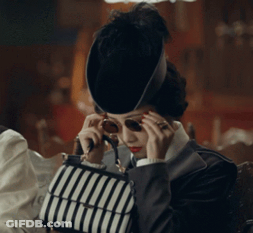 Woman In Hat And Sunglasses Holding Striped Bag GIF