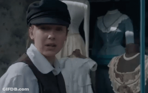 Woman In Hat And Vest In Front Of Window With Mannequins GIF