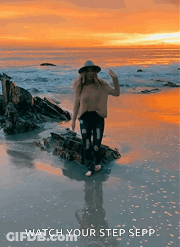 Woman In Hat Standing On Rock At Sunset GIF