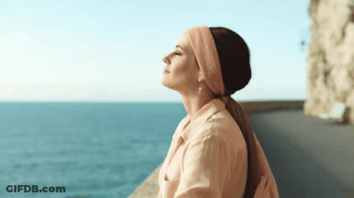 Woman In Headband And Earrings Overlooking Ocean GIF