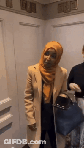 Woman In Hijab And Coat Standing Next To Woman GIF