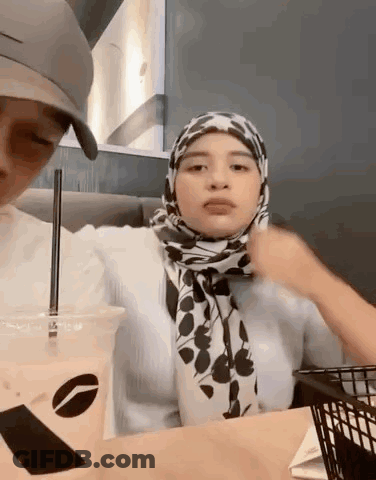 Woman In Hijab Sitting At Table With Coffee And Food Basket GIF