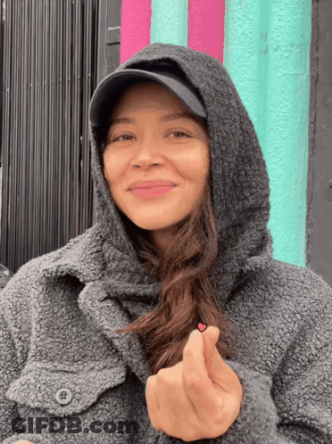 Woman In Hooded Jacket And Hat Making Heart GIF