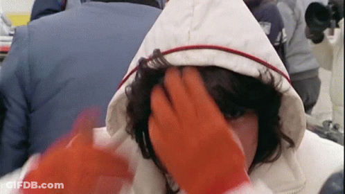 Woman In Hooded Jacket And Orange Gloves Being Patted On Head GIF