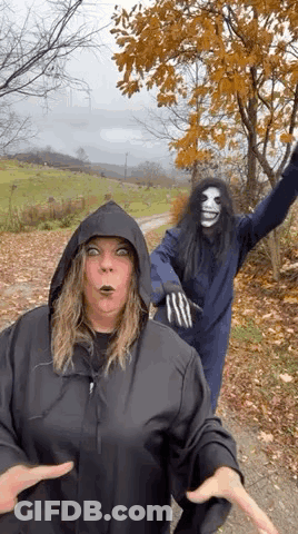 Woman In Hooded Jacket Next To Man In Mask GIF