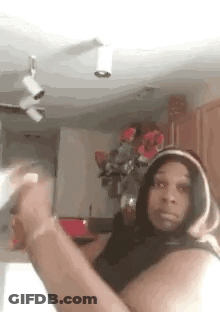 Woman In Hoodie Taking Selfie In Kitchen With Flowers GIF