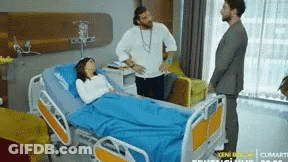 Woman In Hospital Bed Surrounded By Men GIF