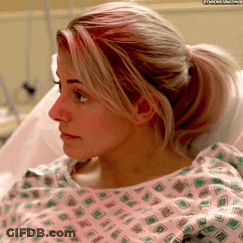 Woman In Hospital Gown With Ponytail Looking At Something GIF