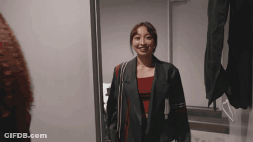 Woman In Jacket Standing Before Mirror GIF