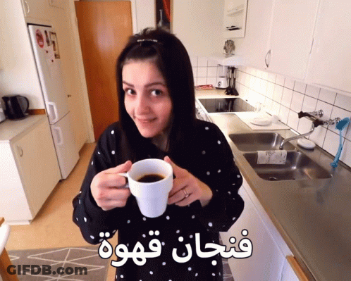 Woman In Kitchen Holding Coffee Cup With Arabic Writing GIF