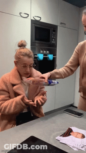 Woman In Kitchen With Baby Picture Behind GIF