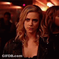 Woman In Leather Jacket Looking At Camera In Dark Room GIF