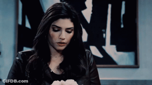Woman In Leather Jacket Looking Down Before Painting Of Man GIF