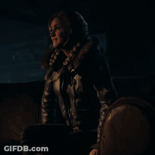 Woman In Leather Jacket Sits On Couch In Dark Room GIF
