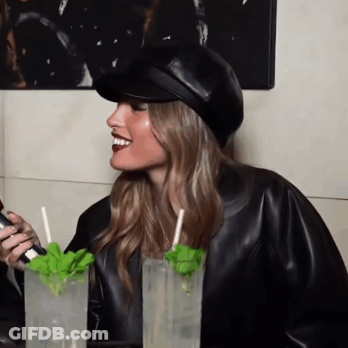 Woman In Leather Jacket Sitting With Drinks GIF