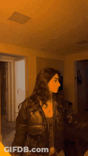 Woman In Leather Jacket Standing By Open Door GIF