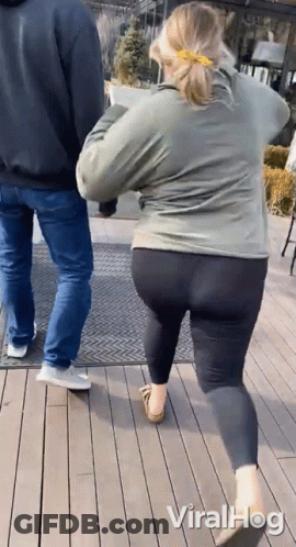 Woman In Leggings Walking Beside Man In Jeans On Wood Deck GIF