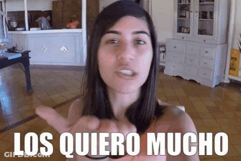 Woman In Living Room With Los Quiero Mucho Behind Her GIF