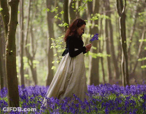 Woman In Long White Dress In Blue Flower Field GIF