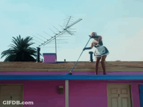 Woman In Maid Outfit Holding Mop On Pink Building Roof GIF