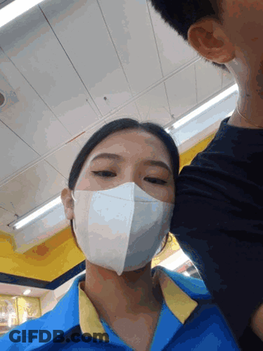 Woman In Mask And Blue Shirt Kissing Man GIF