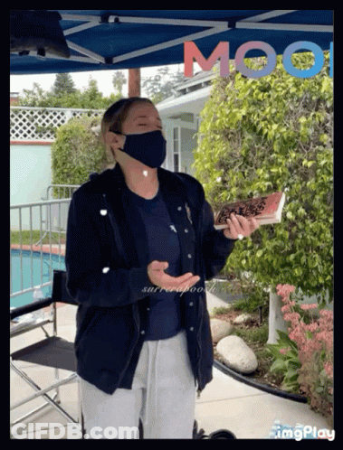 Woman In Mask Holding Book In Front Of Moot Sign GIF