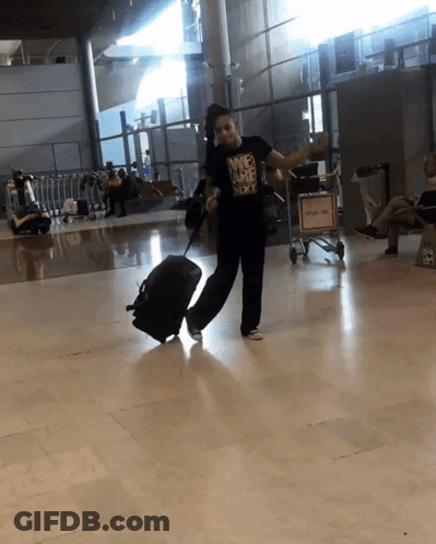 Woman In Nike T-Shirt Holding Suitcase At Airport GIF