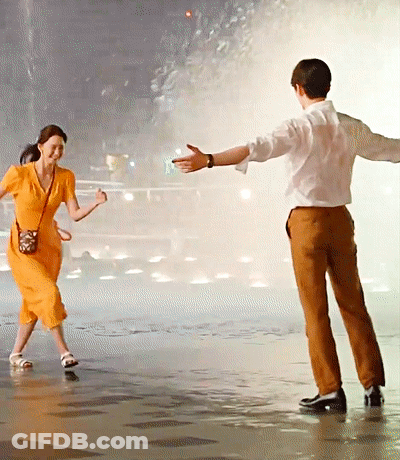 Woman In Orange Dress Dancing With Man In Brown Pants GIF
