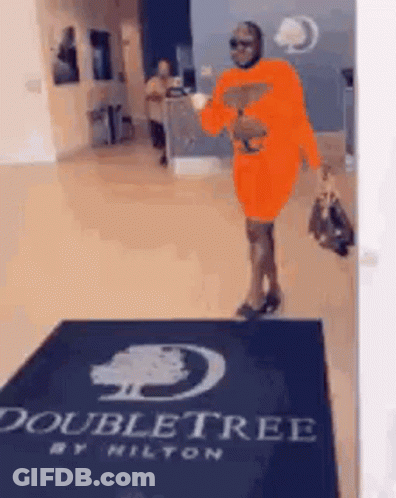 Woman In Orange Dress Walking Through Doubletree Lobby GIF