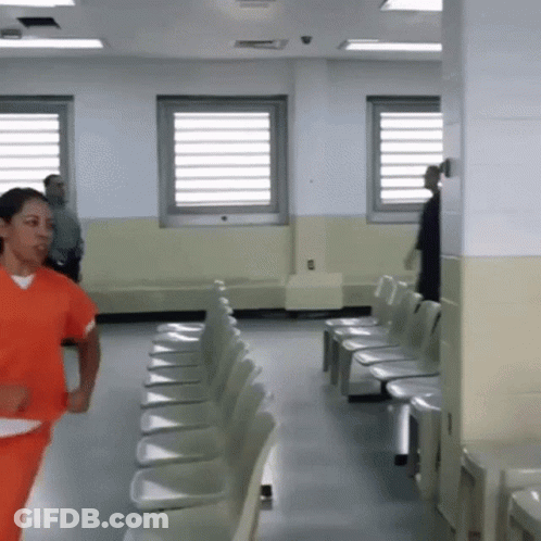 Woman In Orange Scrubs Running Through Chairs GIF