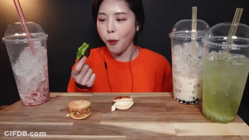 Woman In Orange Shirt Eating Sandwich GIF