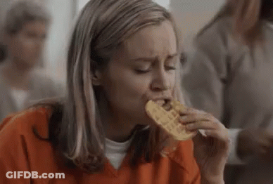 Woman In Orange Shirt Eating Waffle In Jail Cell GIF
