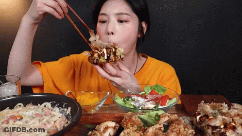 Woman In Orange Shirt Eating With Chopsticks GIF