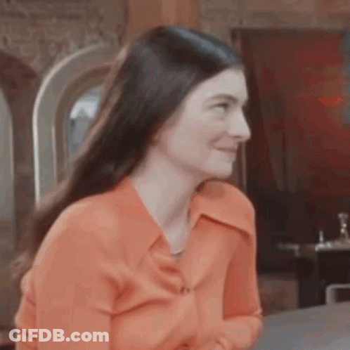 Woman In Orange Shirt Sitting GIF