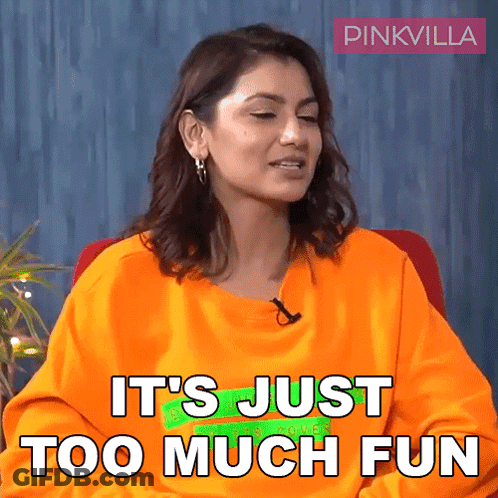 Woman In Orange Shirt Sitting Saying It's Just Too Much Fun GIF