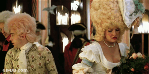 Woman In Pearl Necklace Next To Man In Costume GIF
