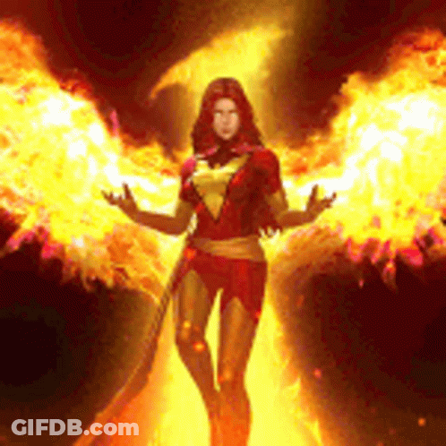 Woman In Phoenix Costume In Front Of Wall Of Fire GIF