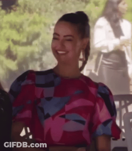 Woman In Pink And Blue Floral Top Smiling At Table GIF