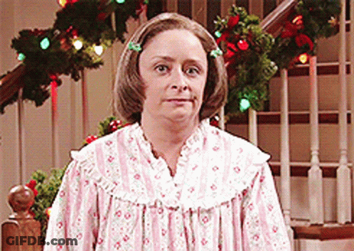 Woman In Pink And White Dress In Front Of Christmas Tree GIF