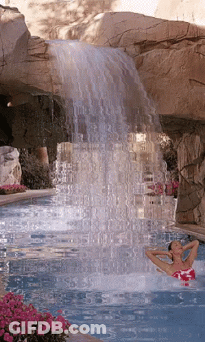 Woman In Pink Bathing Suit Swimming Under Waterfall GIF