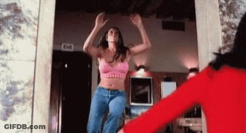 Woman In Pink Bra And Jeans Jumping While Woman In Red Holds Her Hand GIF