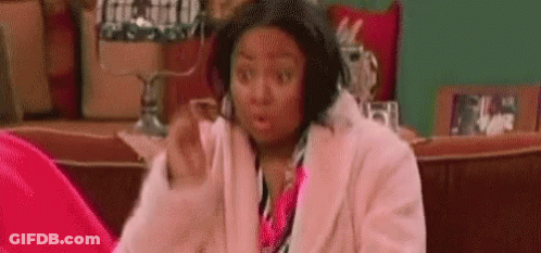 Woman In Pink Coat Surprised On Couch GIF
