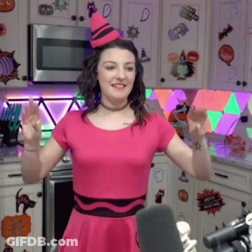 Woman In Pink Dress And Crayon Hat Standing In Kitchen GIF